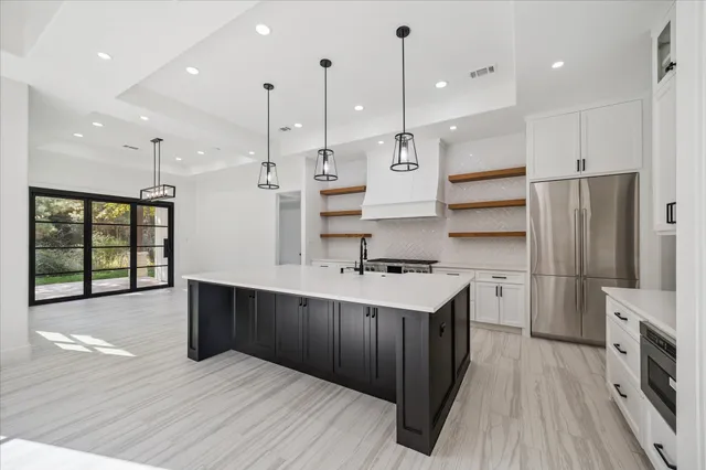 a kitchen with stainless steel appliances granite countertop a refrigerator a sink and a oven