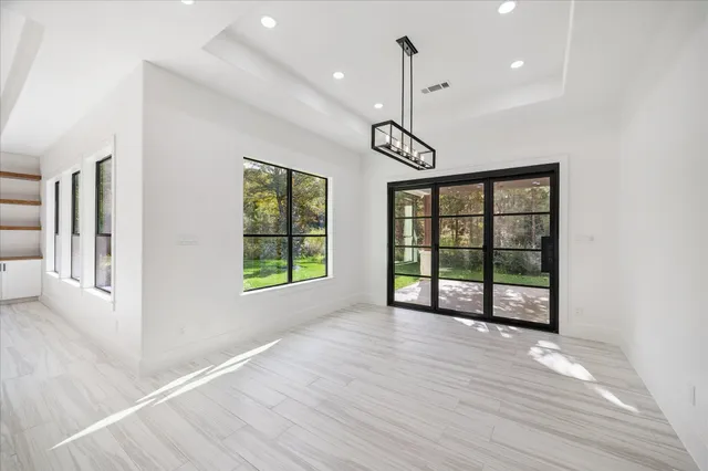 a view of an empty room with window wooden floor and chandelier