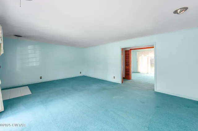 an empty room that has a large mirror and a chandelier fan