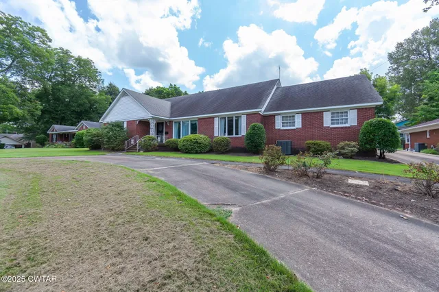 a front view of a house with a garden and trees