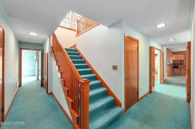 a view of an empty room with window and chandelier fan