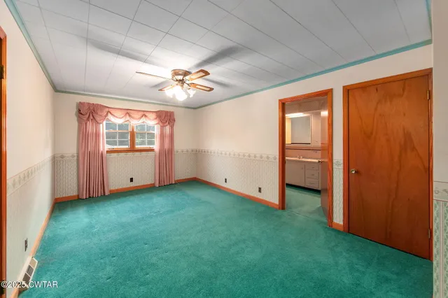 a view of an empty room with wooden floor and fan