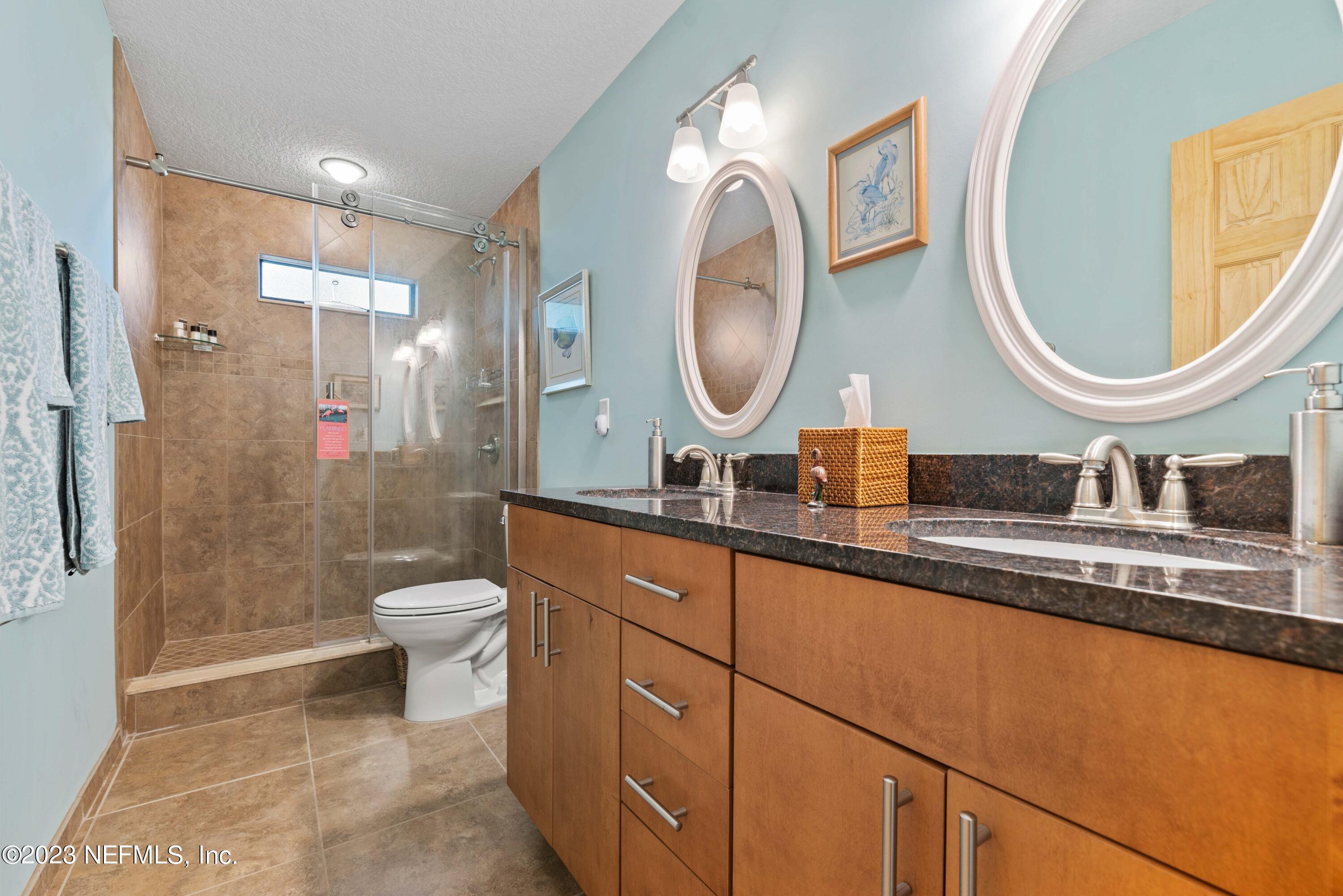 5579 Steamboat Road St. Augustine, FL 32092 - Photo 22 of 52 a bathroom with a granite countertop toilet a sink and a mirror