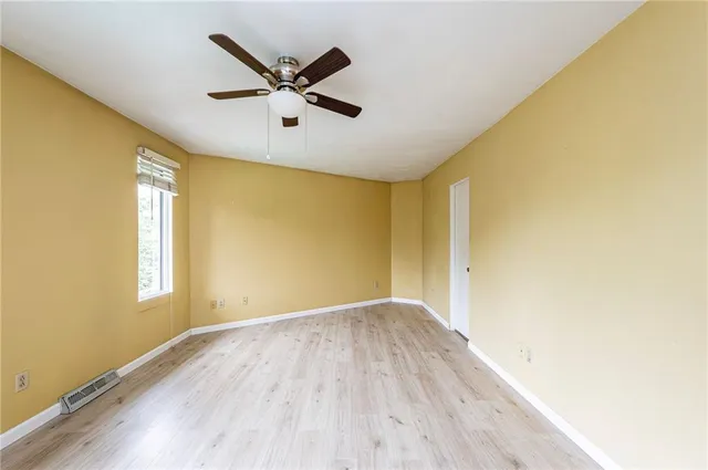 a view of a big room with wooden floor a ceiling fan and windows