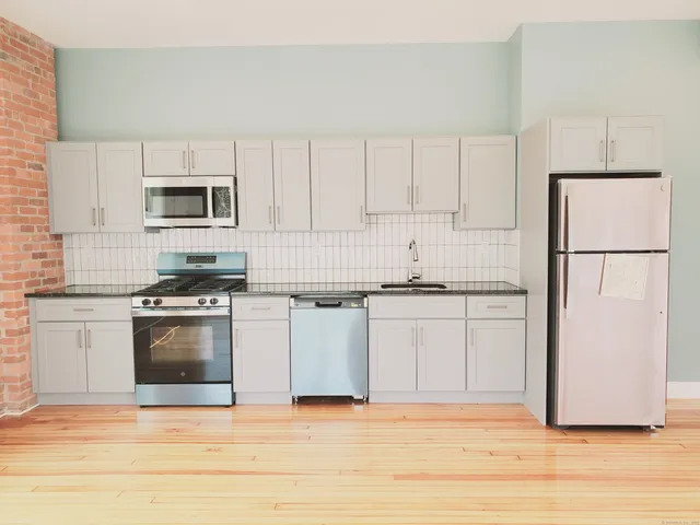 a kitchen with granite countertop white cabinets and stainless steel appliances