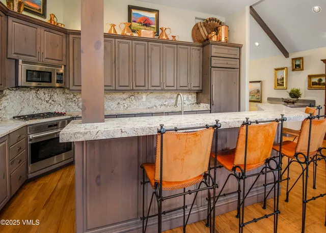 a kitchen with stainless steel appliances granite countertop a stove a sink and a microwave