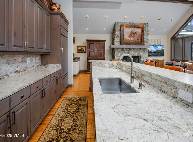 a large kitchen with stainless steel appliances granite countertop a large stove top oven a sink dishwasher and cabinets with wooden floor