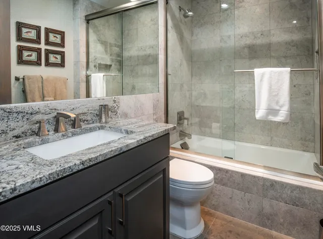 a bathroom with a granite countertop sink a toilet and bathtub