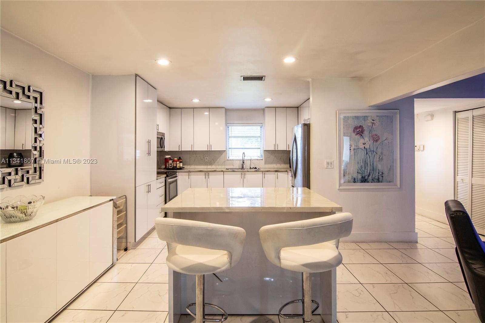 16041 Southwest 284th Street Homestead, FL 33033 - Photo 4 of 20 a kitchen with stainless steel appliances kitchen island granite countertop a refrigerator a stove a sink and white cabinets with wooden floor
