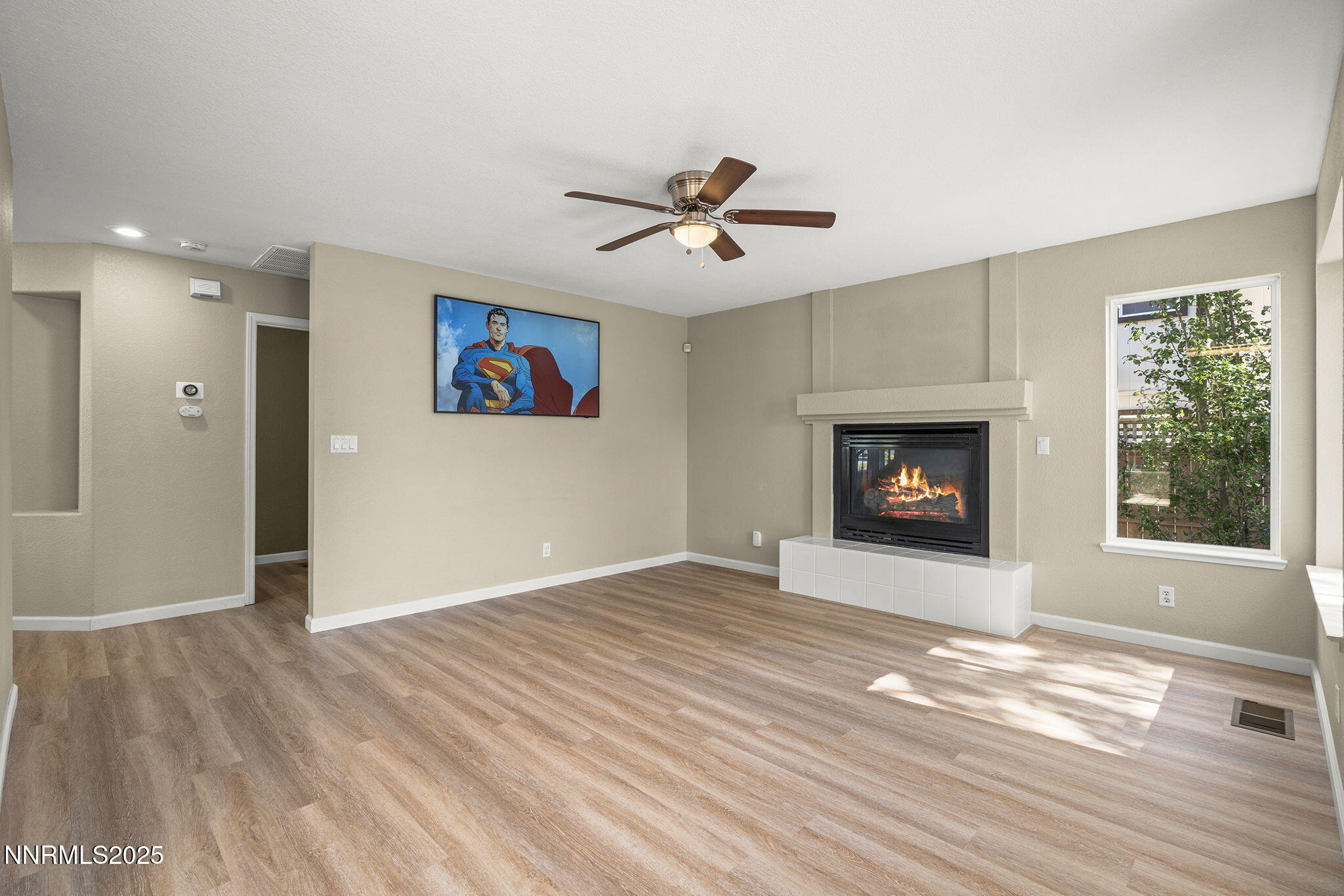 5830 Blue Horizon Drive Reno, NV 89523 - Photo 12 of 41 an empty room with windows a fireplace a ceiling fan and wooden floor