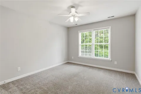 a view of an empty room with a ceiling fan and window