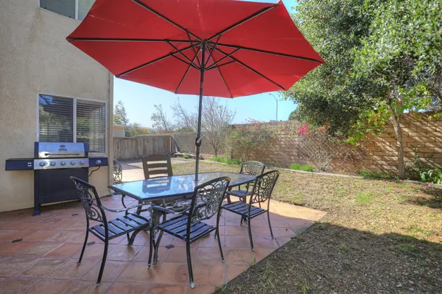 a view of a backyard with table and chairs under an umbrella