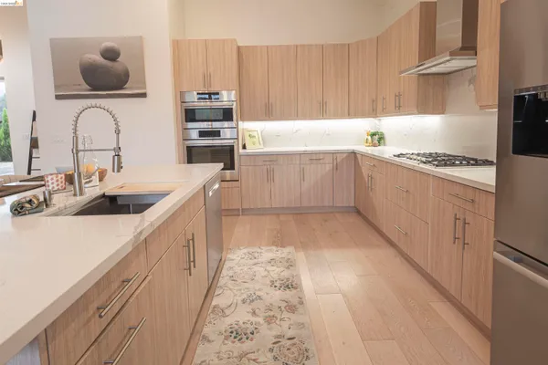 a kitchen with stainless steel appliances granite countertop a dining table chairs stove refrigerator and microwave