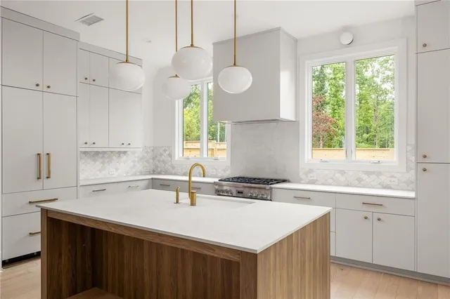 a kitchen with a sink dishwasher a large window with white cabinets and wooden floor