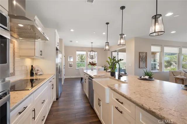 a dining room with wooden floor a chandelier a wooden table and chairs