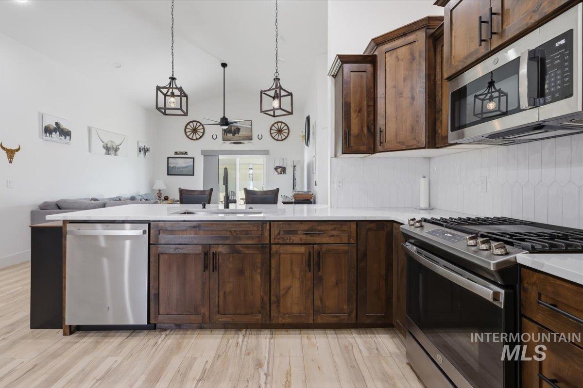 918 Sierra Street Vale, OR 97918 - Photo 15 of 42 Kitchen featuring stainless steel appliances, wood-finish cabinetry, light countertops, and a tile backsplash