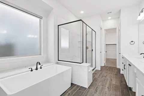a bathroom with a bathtub a double vanity sink and a large mirror
