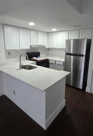 a kitchen with granite countertop a refrigerator and a sink