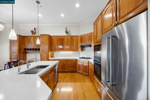 a view of a kitchen with kitchen island a large window wooden floor and stainless steel appliances