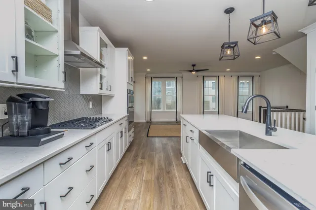 a large kitchen with granite countertop a large center island a sink stainless steel appliances and cabinets