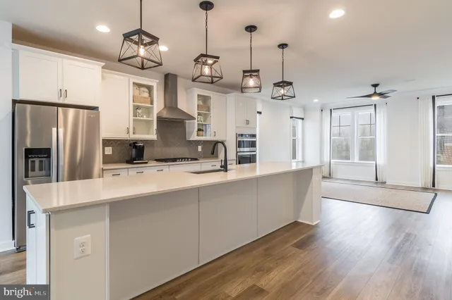 a large kitchen with stainless steel appliances kitchen island granite countertop a refrigerator a oven a island and a sink