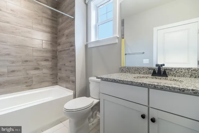 a bathroom with a granite countertop bathtub sink vanity mirror and toilet
