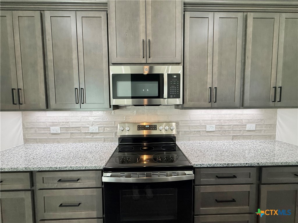 4433 Agave Trail Temple, TX 76502 - Photo 10 of 27 a kitchen with granite countertop cabinets stove and microwave