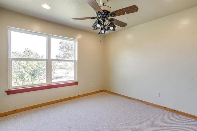 en empty room with windows and ceiling fan
