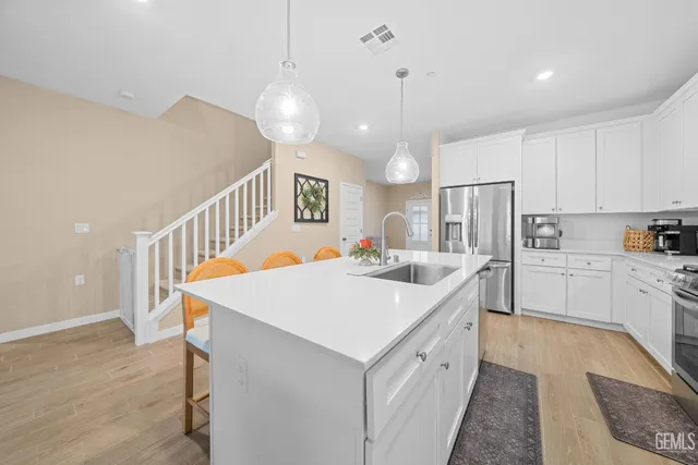 a large white kitchen with a stove a sink a refrigerator and a dining table