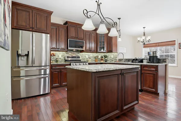 a kitchen with stainless steel appliances granite countertop wooden cabinets a refrigerator a sink and a stove