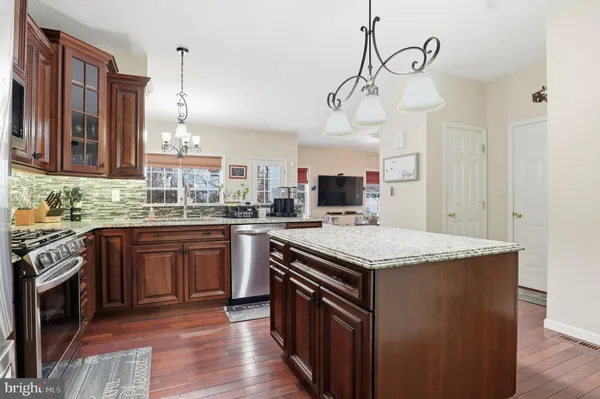 a kitchen with stainless steel appliances granite countertop a sink a stove and a wooden floors