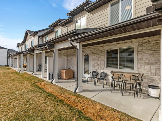3047 Old Emigrant Road, Unit C Syracuse, UT 84075 - Photo 19 of 20 Rear view of property with a patio, stone siding, and a yard