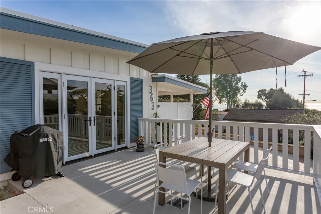 a view of a deck that has a table and chairs under an umbrella