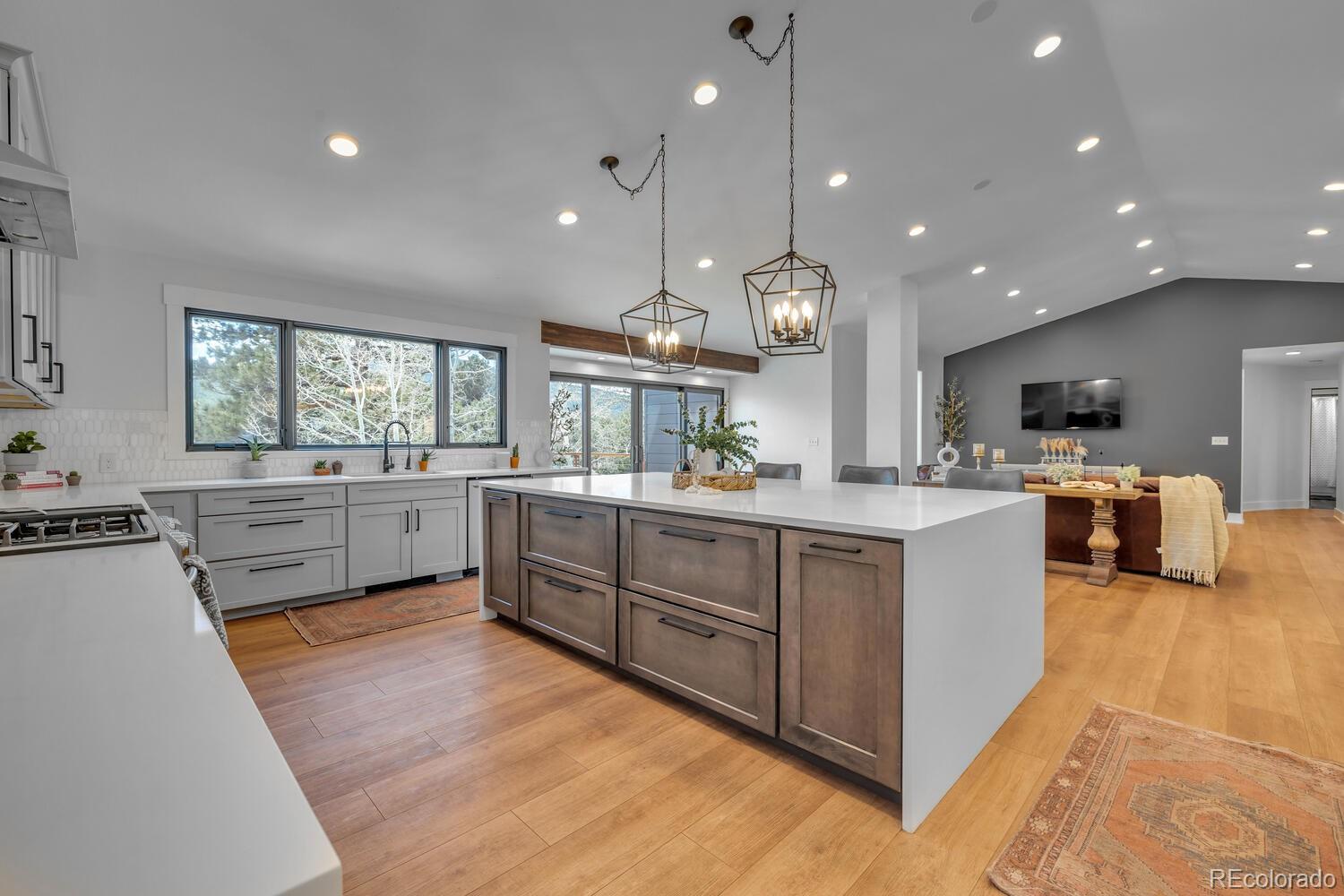 22398 Blue Jay Road Morrison, CO 80465 - Photo 4 of 39 a kitchen with stainless steel appliances kitchen island granite countertop a stove a sink a refrigerator and white cabinets with wooden floor