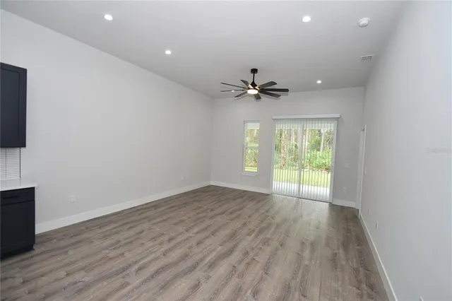a view of an empty room with a window and wooden floor
