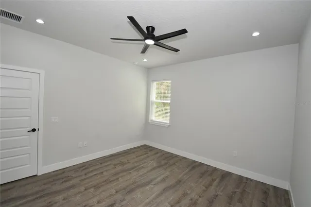 an empty room with wooden floor and ceiling fan
