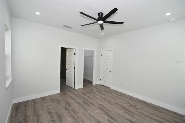 an empty room with wooden floor and a ceiling fan