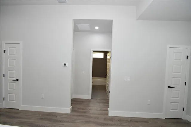 a view of an empty room with wooden floor and closet