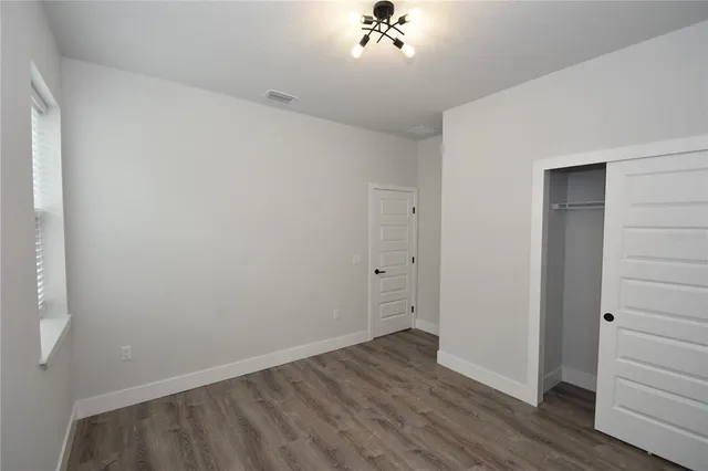 a view of a room with wooden floor and closet area