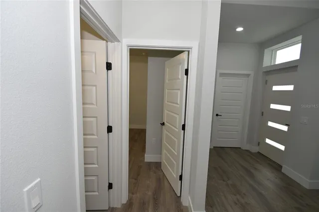 a view of a hallway with wooden floor and bathroom
