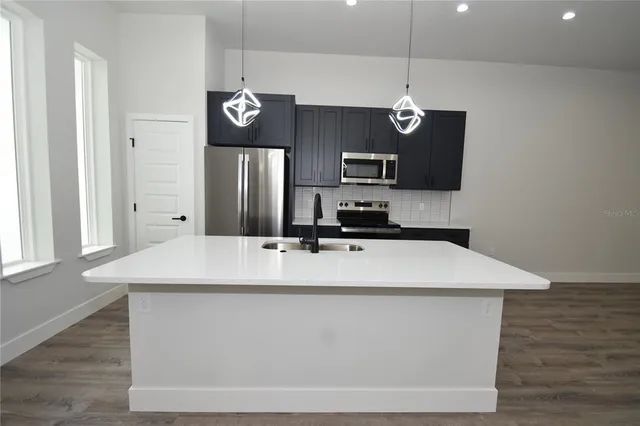 a view of kitchen island with stainless steel appliances granite countertop refrigerator sink and microwave