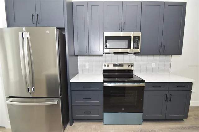 a kitchen with stainless steel appliances a stove microwave and refrigerator