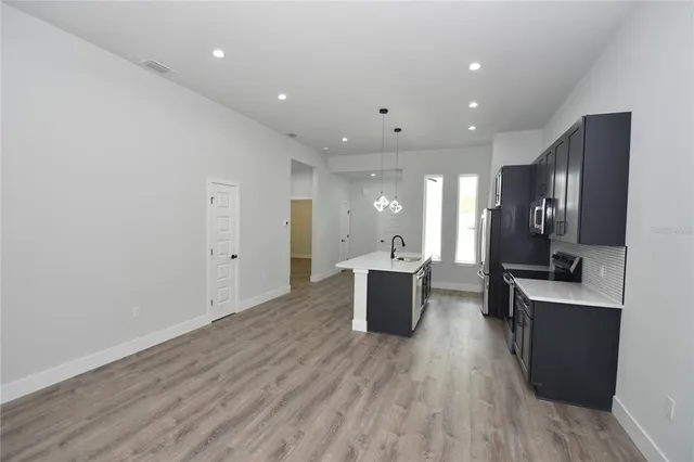 a view of kitchen with stainless steel appliances granite countertop cabinets wooden floor and a window