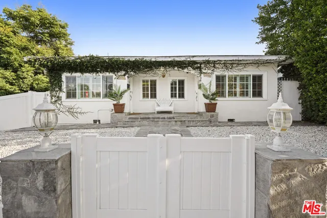 a view of a white house with a tree and plants
