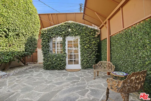 a view of a white house with a bench and potted plants