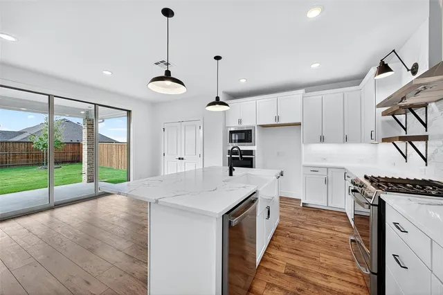 a kitchen with granite countertop a stove a sink a refrigerator and a wooden floor