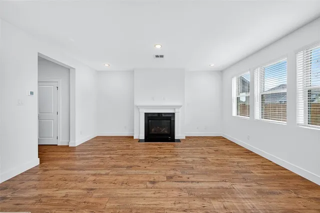 a view of empty room with wooden floor and fireplace