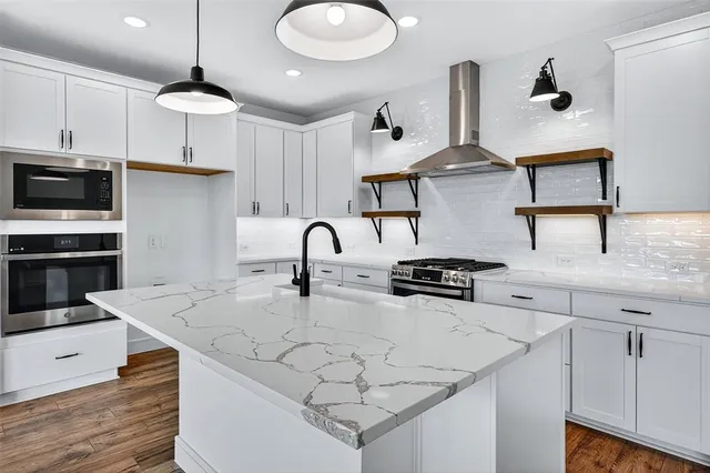 a kitchen with stainless steel appliances granite countertop a sink a stove and refrigerator