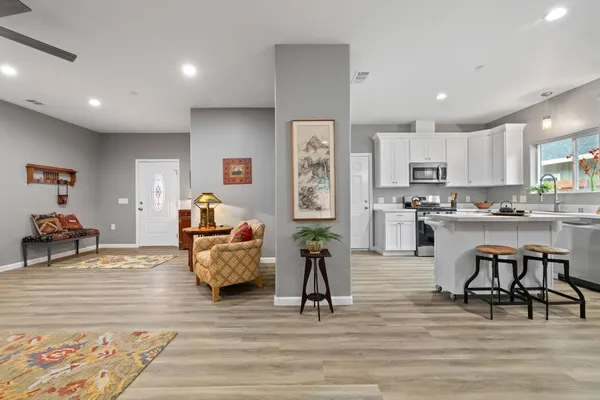 a living room with furniture and kitchen view with wooden floor