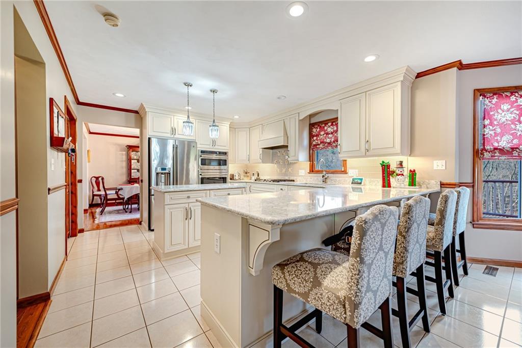 220 Tiffany Irwin, PA 15642 - Photo 11 of 39 a open kitchen with granite countertop a refrigerator a stove top oven and a dining table with wooden floor
